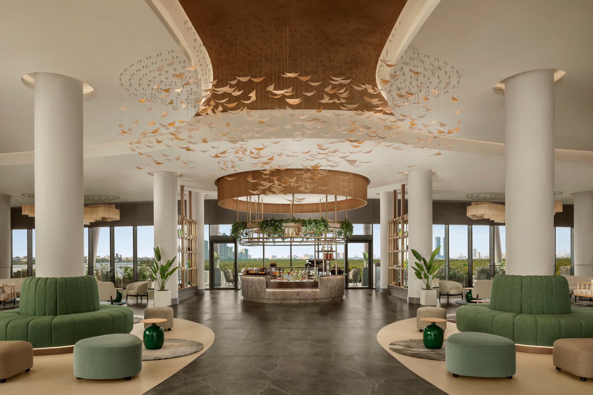Rotana Ras Al Khaimah, The Mangroves — refreshed resort photography of the lobby, with a suspended gold-and-white leaf installation above the central bar and green curved seating framing views to the mangroves