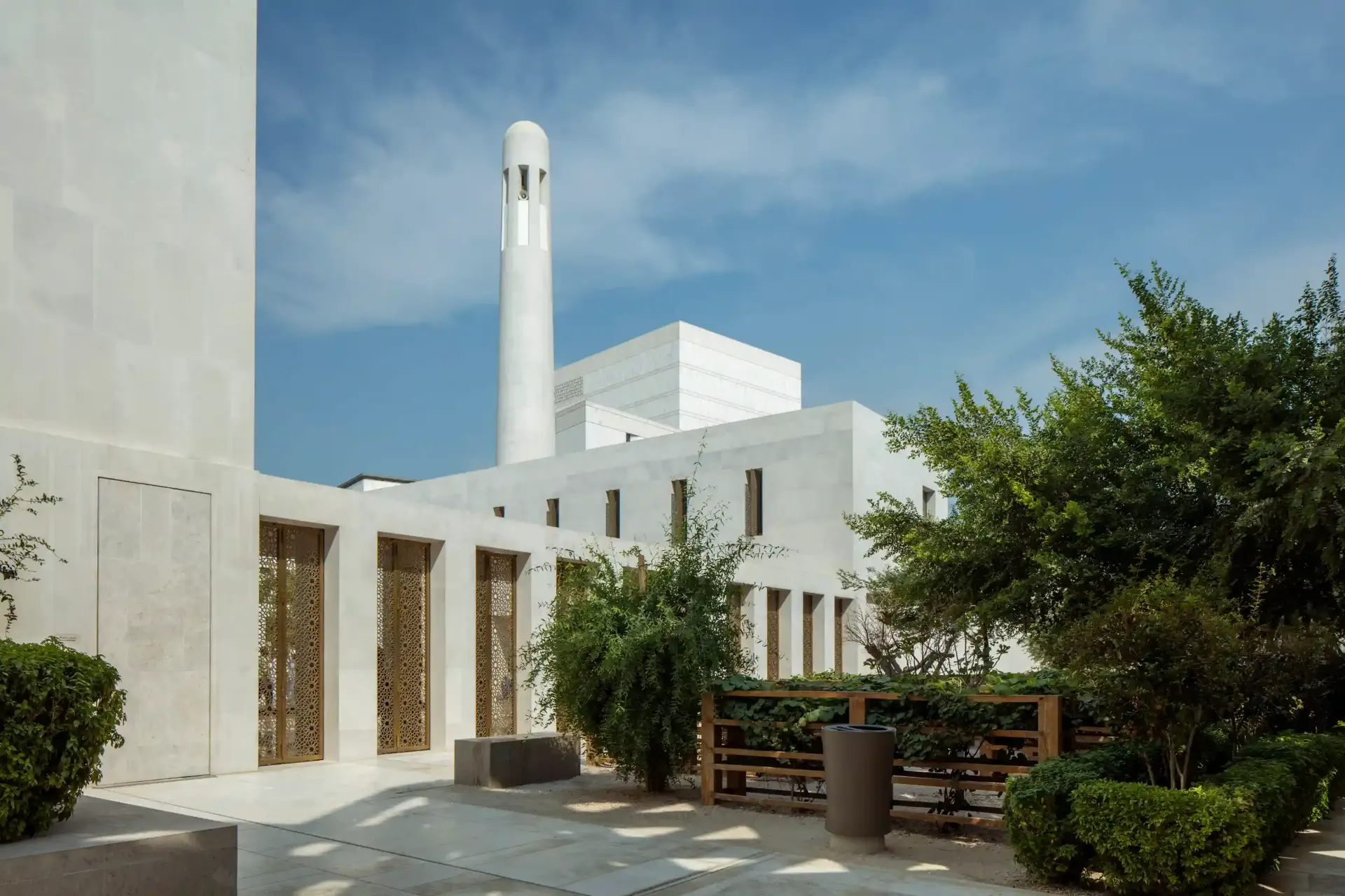 Msheireb Mosque in Downtown Doha, its white minaret and geometric massing against a bright sky, architectural photography by JohnsEye