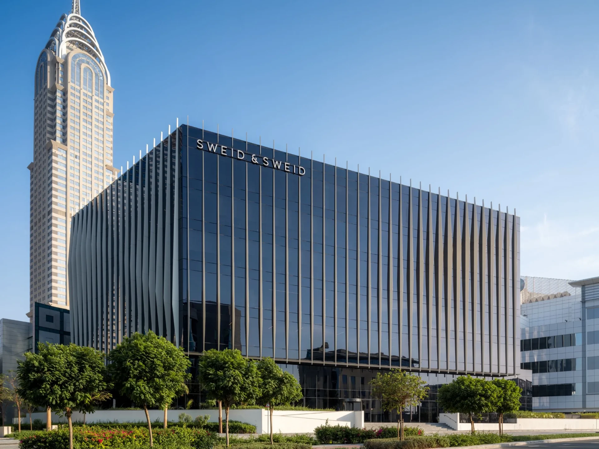 Commercial tower facade in low sun, glazing reflecting the neighbouring skyline across its full height
