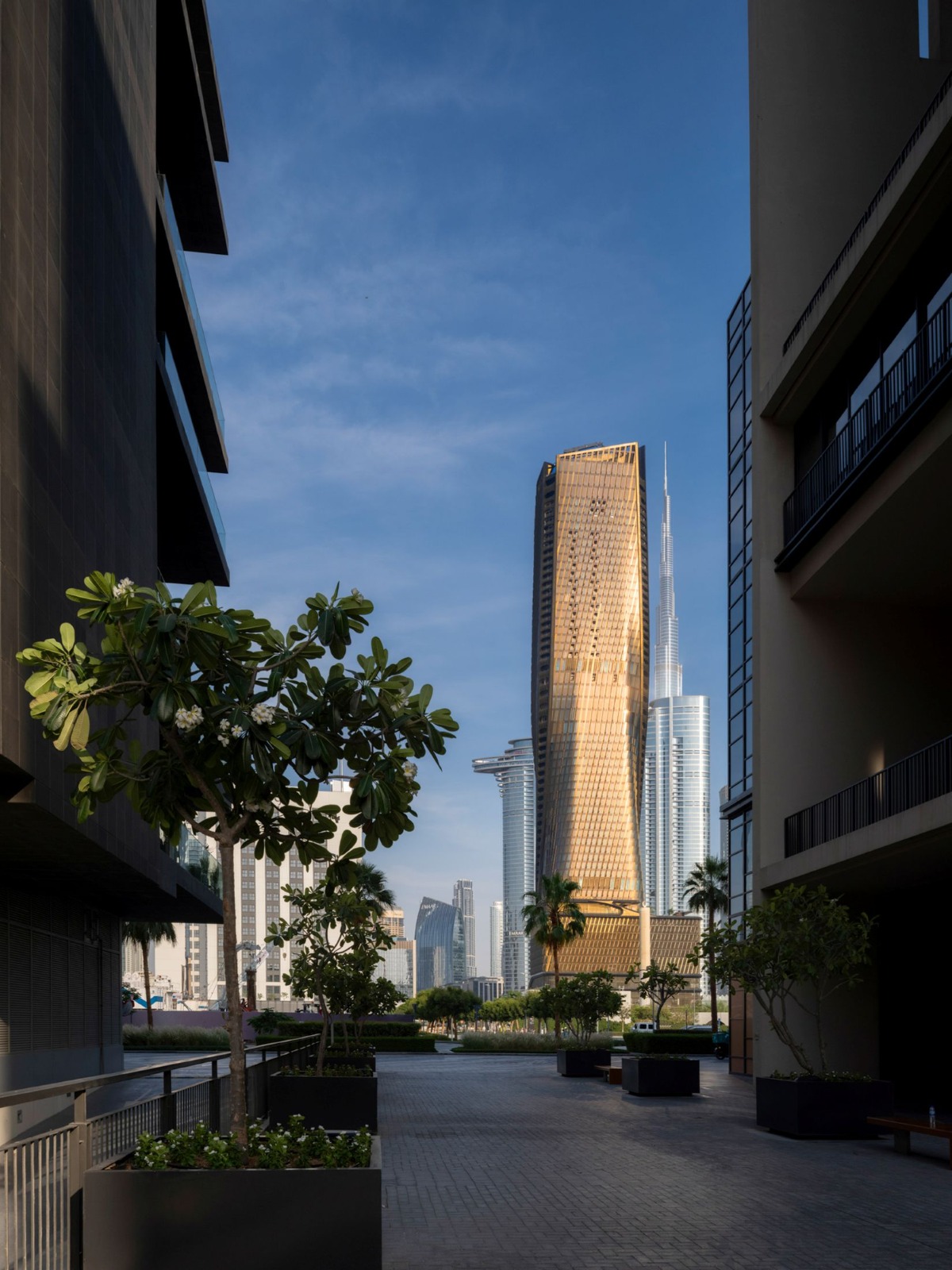 Framed plaza and alley composition showing Wasl Tower with Burj Khalifa behind